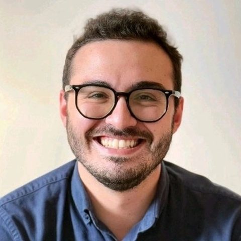 Artur Batissoco, fundador do MuralDaSaúde, sorrindo, de óculos e camisa azul